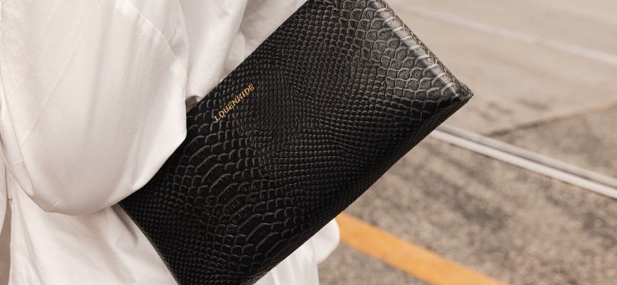 Faux Black Croc Handbag swings from womans shoulder