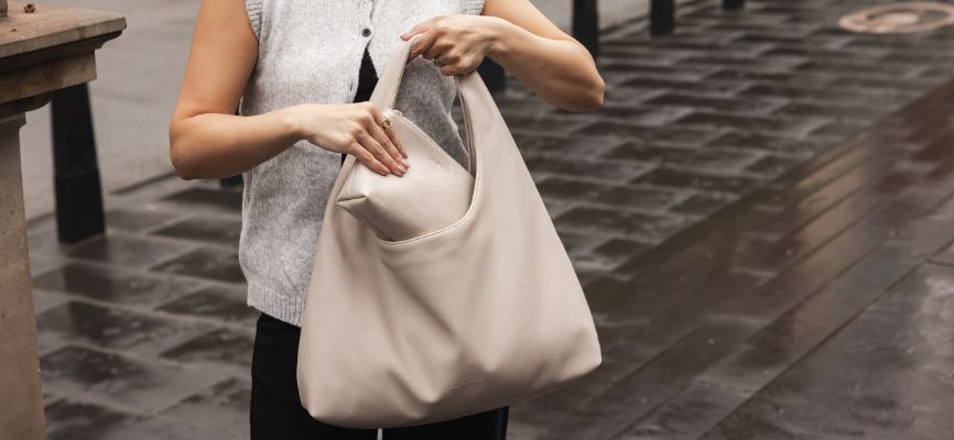 Woman slips Cream Pouch into Cream Handbag