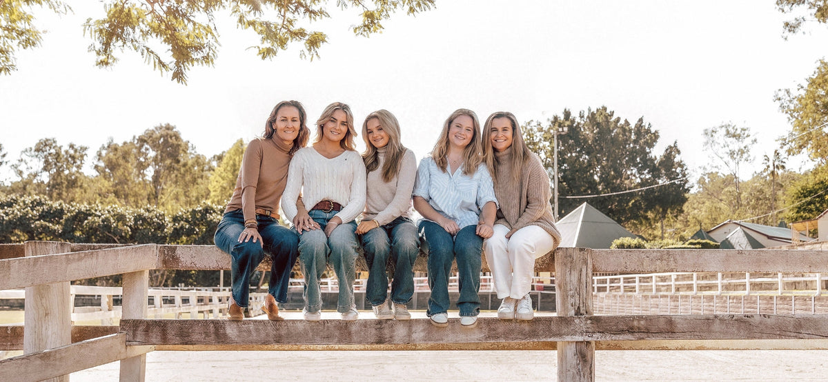 Two mother's sit with three daughters on a fence in a rural Australian property
