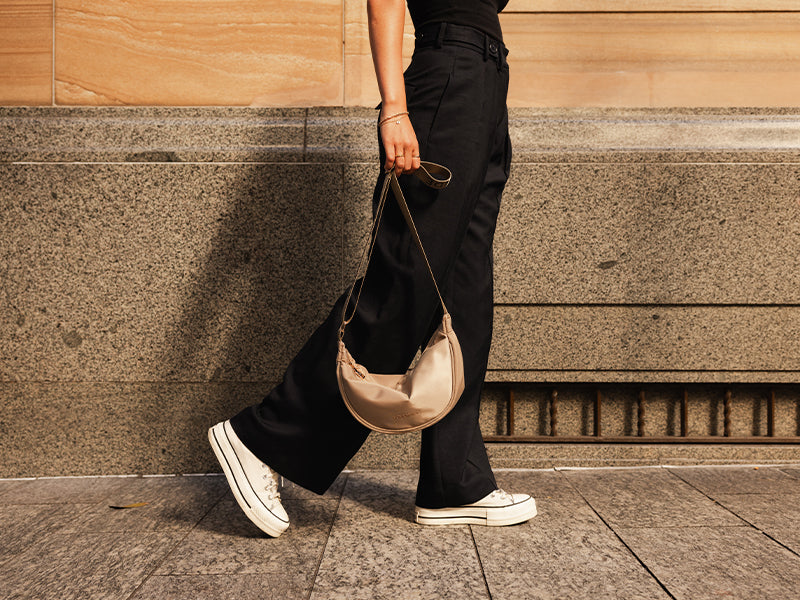 A woman walking with a beige crossbody bag