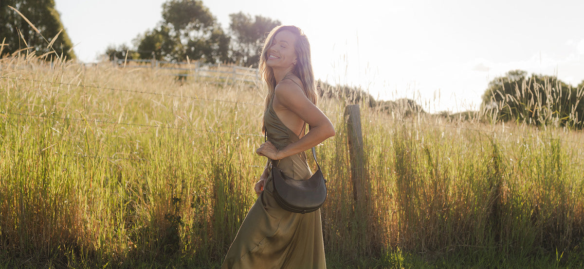 Travel Crossbody Bag is slung across woman's chest, as she stands in a field