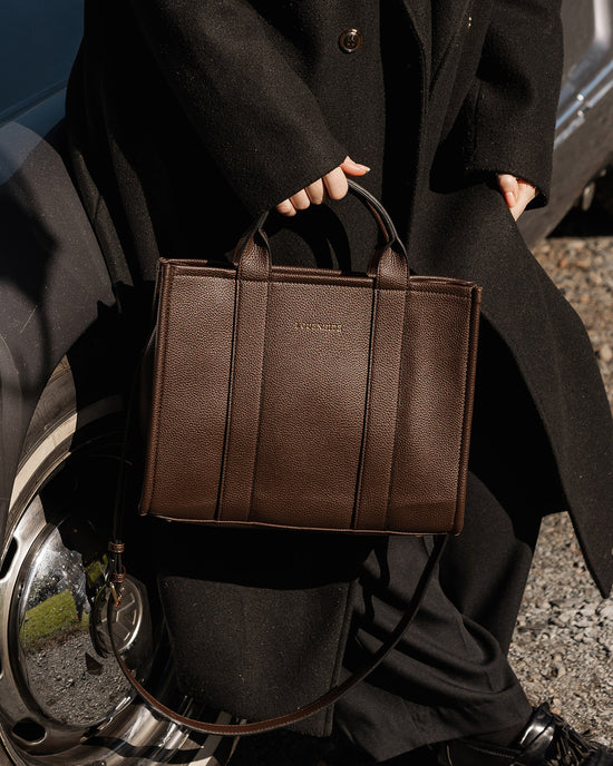 Louenhide Manhattan Tote Bag in brown vegan leather styled with black coat outdoors
